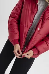 Campera color rojo, acolchada y con capucha, de corte amplio y cierre frontal.