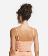 Blusa cropped color durazno con estampado de flores blancas, escote en V, breteles finos y detalle retorcido en el frente.