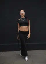Conjunto de top corto negro de un solo hombro y falda larga negra con cordones laterales.
