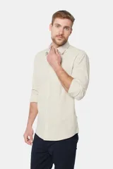 Camisa de lino color beige, de manga larga, con cuello clásico y bolsillo en el pecho.