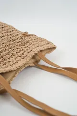 Bolso tipo tote bag color beige, tejido a crochet, con asas de cuero marrón y cordones laterales ajustables.