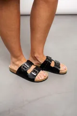 Sandalias negras con dos tiras anchas ajustables con hebillas plateadas y detalle de tachas plateadas.