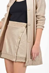 Conjunto dorado que incluye camisola de botones y pollera corta a juego.
