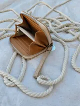 Billetera pequeña de cuero color beige con textura croco, forrada, con cierre metálico y pulsera de cuero.