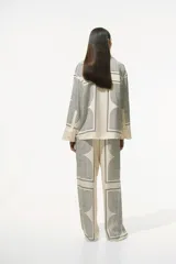 Pantalón de corte recto color crema con estampado geométrico en negro. Modelo de tiro alto con elástico en la parte posterior de la pretina y cierre oculto en un lateral.