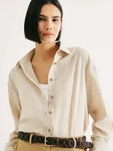 Camisa de manga larga con rayas verticales color naranja y blanco, con cuello camisero y cierre con botones.