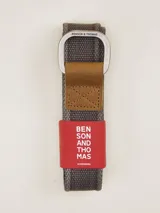 Cinturón de tela color beige con hebilla metálica doble cuadrada y aplique de cuero marrón.