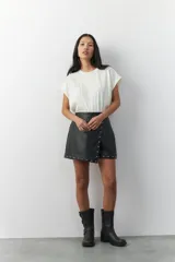 Short tipo pollera en símil cuero negro, con apliques de tachas en la parte frontal.