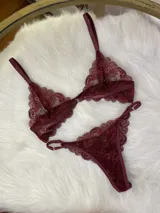 Conjunto de lencería de encaje bordó oscuro, compuesto por un corpiño triangular con breteles regulables y broche delantero, y una tanga regulable.