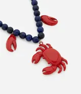 Collar de cuentas azules con colgante de cangrejo rojo y pinzas rojas colgantes.