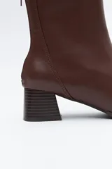 Bota corta de caña elástica color negro, con puntera cuadrada y taco geométrico de altura media. Presenta cierre de cremallera en la parte trasera.