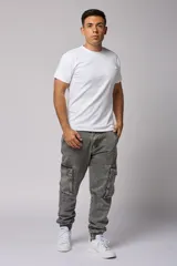 Pantalón jean gris claro, estilo jogger, con bolsillos cargo laterales y puños elásticos en los tobillos.