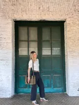 Cartera tipo tote bag de cuero color verde oliva, con doble asa corta de cuero marrón y correa larga extraíble y regulable de cuero marrón. Tiene un bolsillo frontal con cierre y un bolsillo interno.