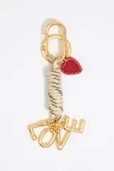 Llavero con mosquetón metálico dorado y dije de corazón rojo. Presenta un cabo anudado en color marfil con motas negras del cual cuelgan letras metálicas doradas formando la palabra 'LOVE'.