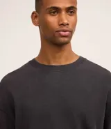 Remera negra de corte boxy con cuello redondo y mangas cortas. Tejido con textura waffle.