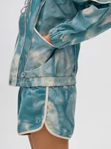 Campera rompevientos estilo biker con capucha desmontable, color celeste con estampado de nubes blancas y detalles en blanco.