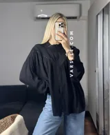Camisa blanca de mangas largas con detalles de encaje en el cuello y en el frente.