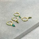 Aros dorados tipo argolla con incrustaciones de circonitas verdes y dije colgante de circonita verde en forma de lágrima.