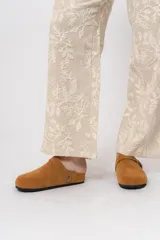 Zueco de gamuza color marrón, con detalles de costuras y hebilla metálica ajustable.