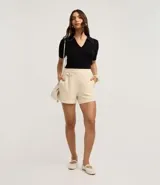 Blusa de punto color blanco, con cuello polo, escote en V y mangas cortas. Detalle de mini perlas aplicadas en el cuello.