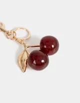 Llavero con dije de cerezas rojas con glitter y hojas doradas, con mosquetón metálico dorado.