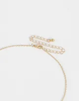 Collar corto dorado con cadena de eslabones y perlas, con ramillete de dijes folk: bota campera, corazón y moneda con perla.