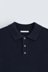 Polo azul marino de punto con cuello solapa, cierre frontal de botonadura, manga corta y rib en los puños y el bajo.