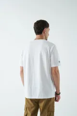 Remera blanca de algodón con estampado frontal de texto en azul y naranja. Corte clásico y cuello redondo.