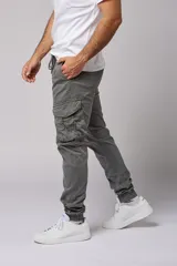Pantalón cargo color beige de gabardina, con corte ajustado, bolsillos laterales con fuelle y puños elásticos en los tobillos.