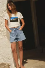 Remera blanca de algodón con cuello redondo y mangas cortas. Estampado rectangular con el letrero de Hollywood sobre una colina y cielo azul.