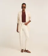 Pantalón slim de jeans color blanco, con cintura mediana, bolsillos delanteros y traseros, cierre con botón y cremallera, y aberturas en el ruedo.