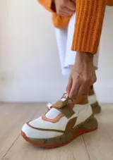 Zapatillas deportivas blancas con detalles en cuero color salmón y suela gruesa con detalles en naranja.