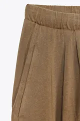 Pantalón color marrón claro, de tiro medio, corte ancho y largo tobillero. Cuenta con cintura elástica ajustable con cordones y bolsillos laterales ocultos en la costura.