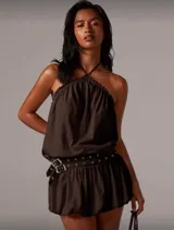 Vestido corto marrón con cuello halter y falda globo con cinturón con ojales y hebilla metálica.