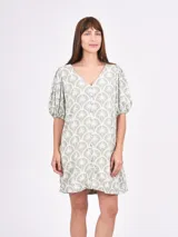 Vestido corto color verde con estampado de palmeras blancas, escote en V y mangas cortas abullonadas.