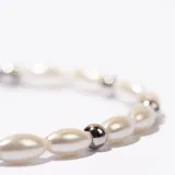 Pulsera de perlas sintéticas color crema, con cuentas plateadas y cierre de mosquetón.