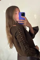 Camisa corta marrón de cuero ovino desgastado con cuello clásico, cierre frontal con botones y mangas largas con aberturas.