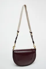 Bolso de hombro ovalado negro con asa de doble tira redonda con detalles metalizados dorados. Cierre imantado y asa de bandolera extraíble con tejido a contraste. Bolso interior con cierre mediante cremallera metálica.