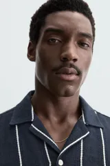 Camisa de hombre a rayas verticales color beige y blanco, de corte relaxed fit, manga corta y cuello bowling.