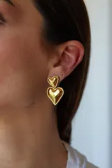 Aros colgantes dorados con forma de corazón doble.