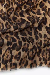 Pañuelo rectangular con estampado de leopardo en tonos marrón y negro, con terminaciones desflecadas.