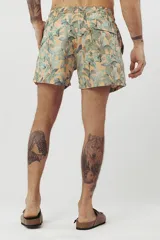 Short de baño con estampado de hojas de palmera en tonos beige, verde y naranja.