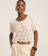 Blusa color crudo de ganchillo con mangas cortas abullonadas y bordados de flores.