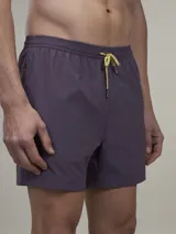 Short de baño verde con estampado de margaritas blancas y cordón ajustable naranja.