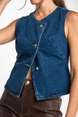 Chaleco de denim azul con cierre cruzado con botones metálicos.