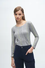 Remera gris de corte ajustado, con cuello redondo y mangas largas. Presenta líneas verticales bordadas en color verde claro y blanco.