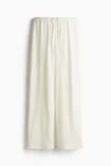 Pantalón recto color crema, de tejido arrugado suave, con cintura elástica y cordón ajustable.