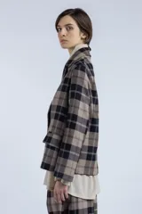 Blazer marrón con estampado a cuadros negros y blancos, de corte recto, solapa clásica, cierre cruzado con botones y bolsillos frontales.