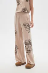 Pantalón ancho color beige con estampado de hojas negras.