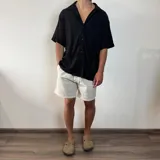 Bermuda negra de lino con corte arriba de la rodilla y cordón ajustable en la cintura.